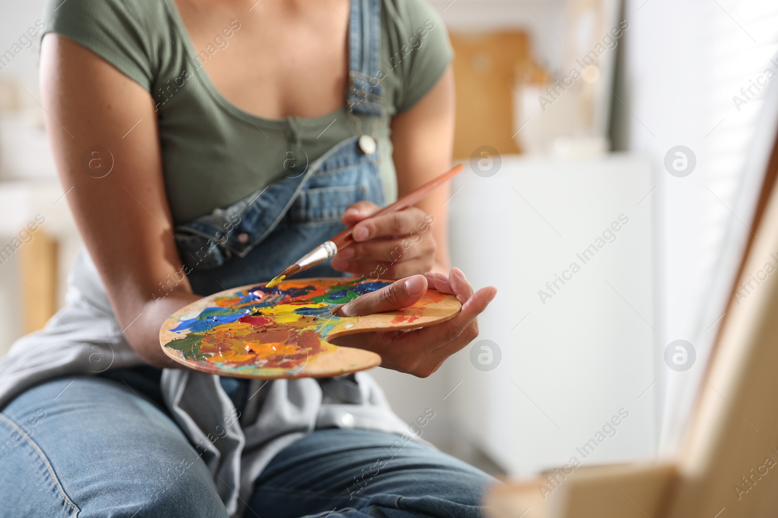 Photo of Woman drawing picture with paint in studio, closeup