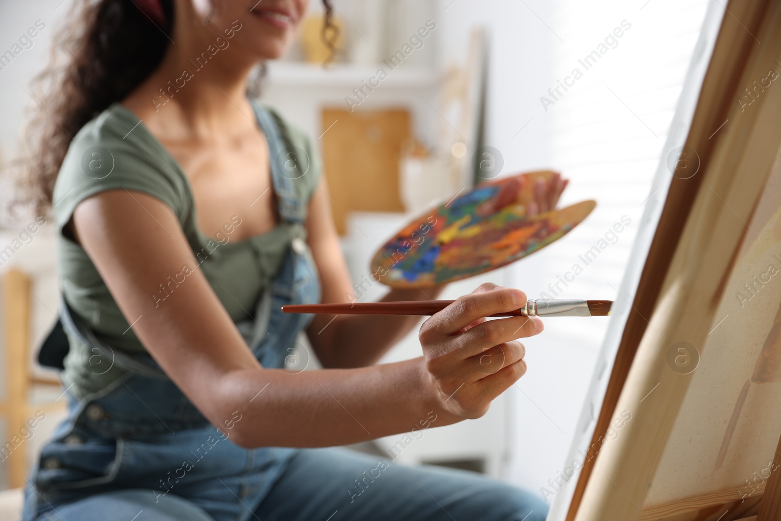 Photo of Smiling woman drawing picture with paint in studio, closeup