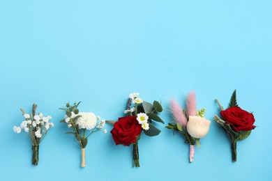 Many stylish boutonnieres on light blue background, flat lay. Space for text