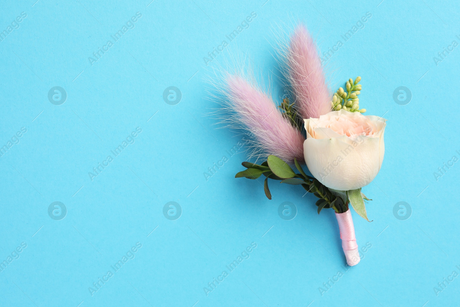 Photo of Small stylish boutonniere on light blue background, top view. Space for text