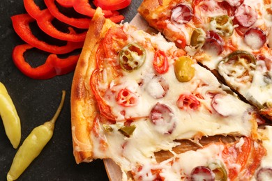 Photo of Delicious pizza Diablo and peppers on dark table, flat lay