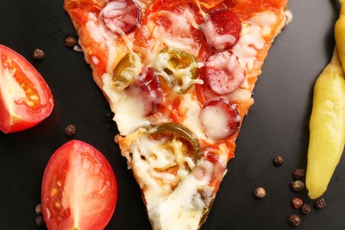 Photo of Delicious pizza Diablo, peppercorns, tomato and pepper on black plate, flat lay