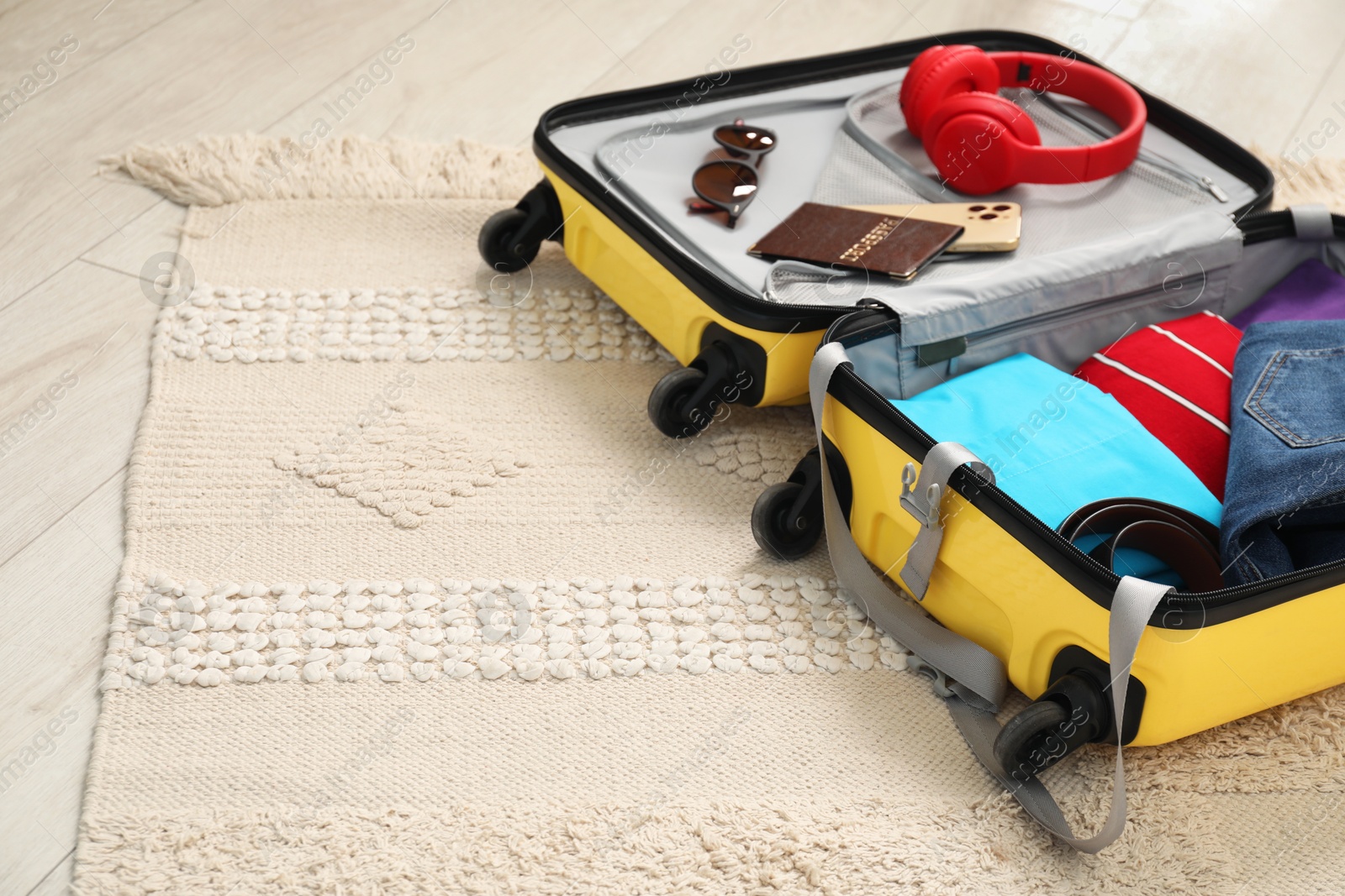 Photo of Open suitcase with traveler's belongings on floor, space for text