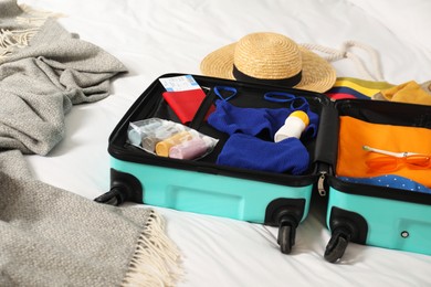 Open suitcase with traveler's belongings on bed