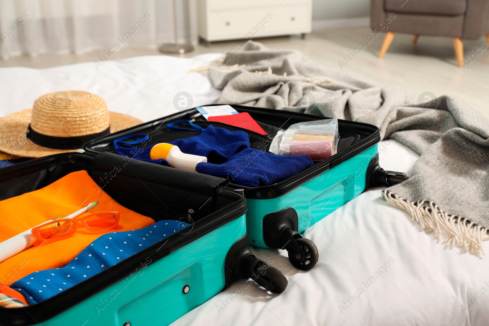 Photo of Open suitcase with traveler's belongings on bed