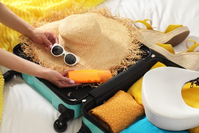 Woman packing suitcase for trip in bedroom, closeup