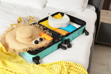 Photo of Open suitcase with traveler's belongings on bed