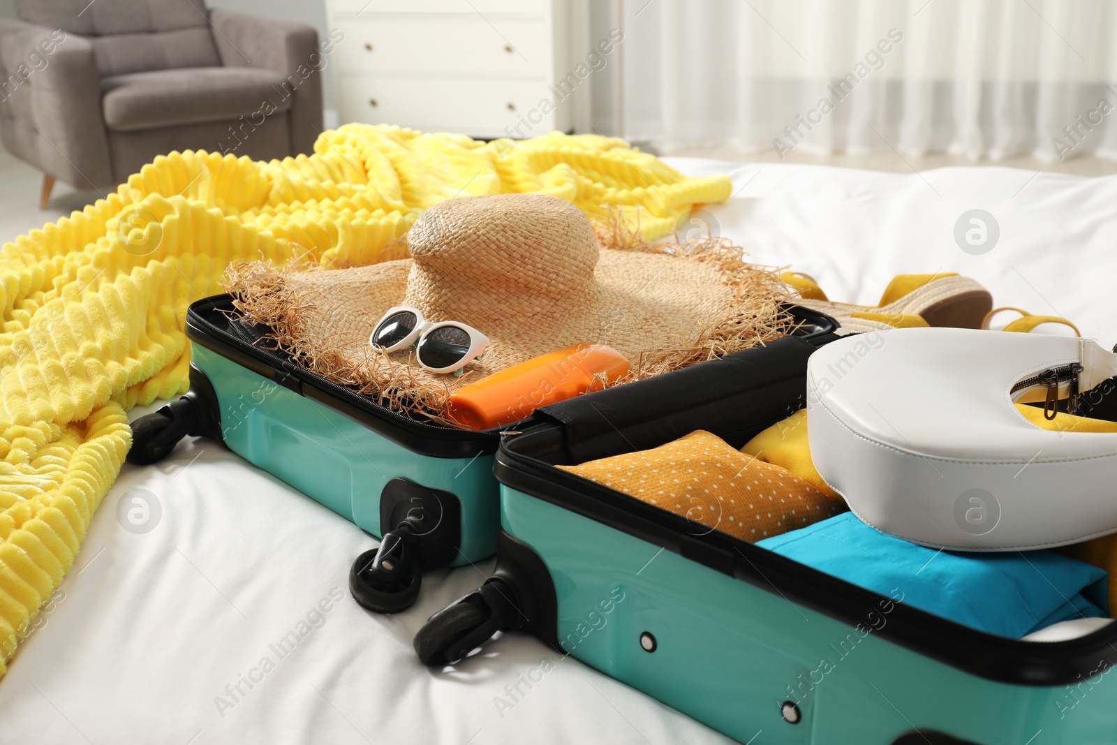 Photo of Open suitcase with traveler's belongings on bed, closeup