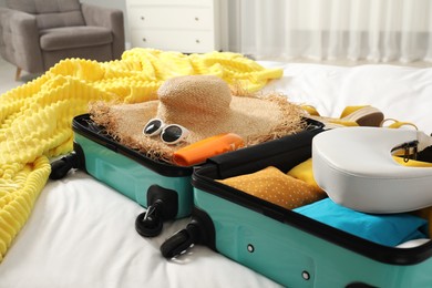 Photo of Open suitcase with traveler's belongings on bed, closeup