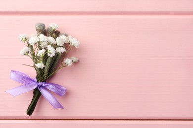 Small stylish boutonniere on pink wooden table, top view. Space for text