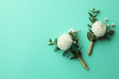 Small stylish boutonnieres on turquoise background, flat lay. Space for text