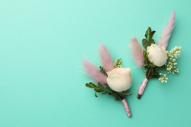 Small stylish boutonnieres on turquoise background, flat lay. Space for text