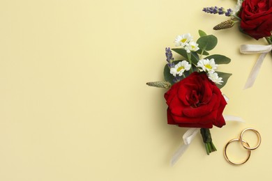 Small stylish boutonnieres and rings on beige background, flat lay. Space for text