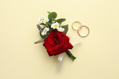 Photo of Small stylish boutonniere and rings on beige background, flat lay