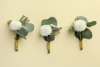 Many stylish boutonnieres on beige background, flat lay