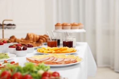 Different meals served on white table indoors, selective focus. Buffet menu