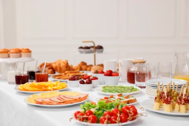 Different meals served on white table indoors. Buffet menu