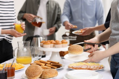 Coworkers having business lunch at white table indoors, closeup