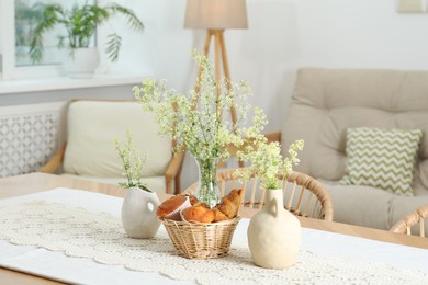 Fresh pastries and beautiful flowers on table in stylish dining room