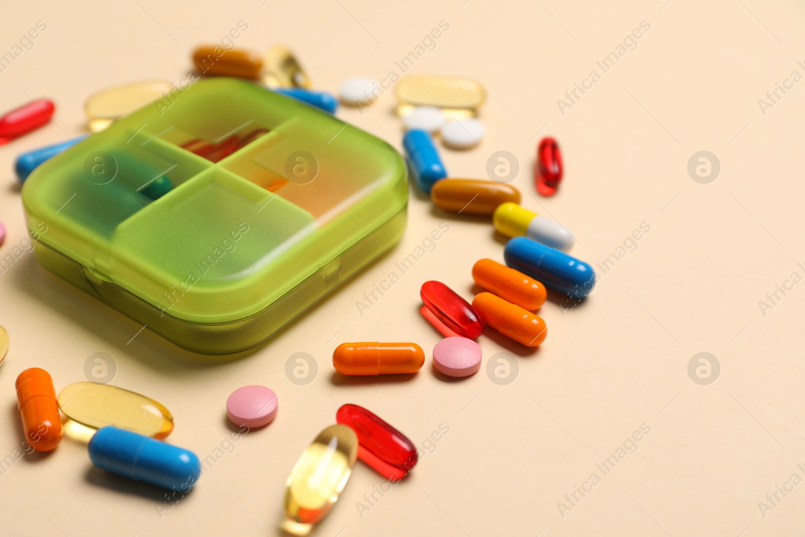 Photo of Different pills and organizer on beige background, closeup. Space for text