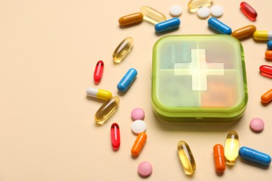 Different pills and organizer on beige background, closeup. Space for text