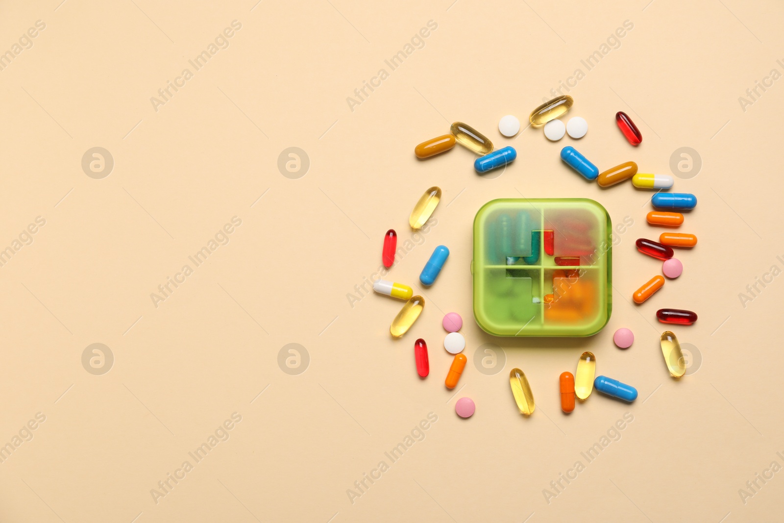 Photo of Different pills and organizer on beige background, flat lay. Space for text