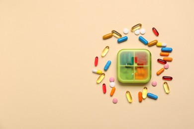 Photo of Different pills and organizer on beige background, flat lay. Space for text