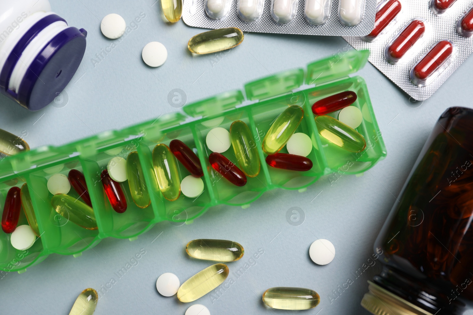 Photo of Different pills, organizer and medical jars on light background, flat lay