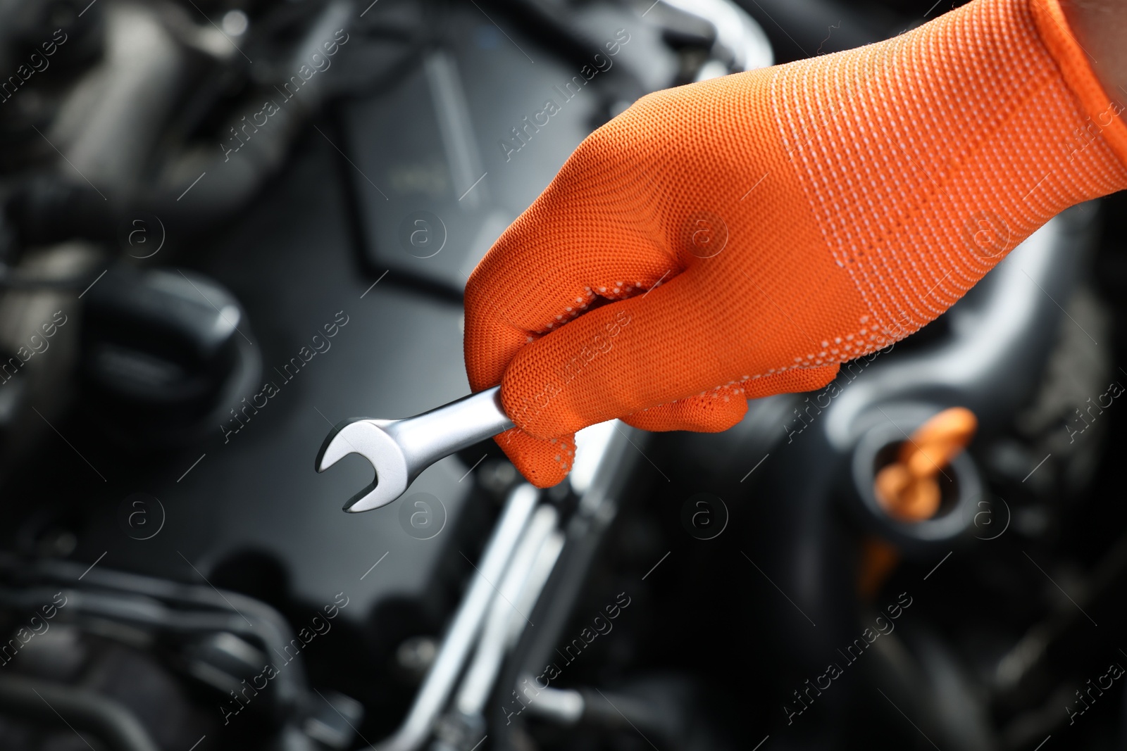 Photo of Auto mechanic with ratcheting wrench fixing car at automobile repair shop, closeup