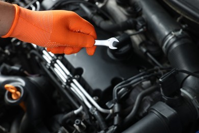 Photo of Auto mechanic with ratcheting wrench fixing car at automobile repair shop, closeup