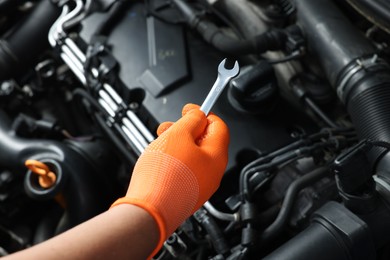 Photo of Auto mechanic with ratcheting wrench fixing car at automobile repair shop, closeup