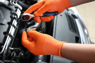 Auto mechanic with torque wrench fixing car at automobile repair shop, closeup