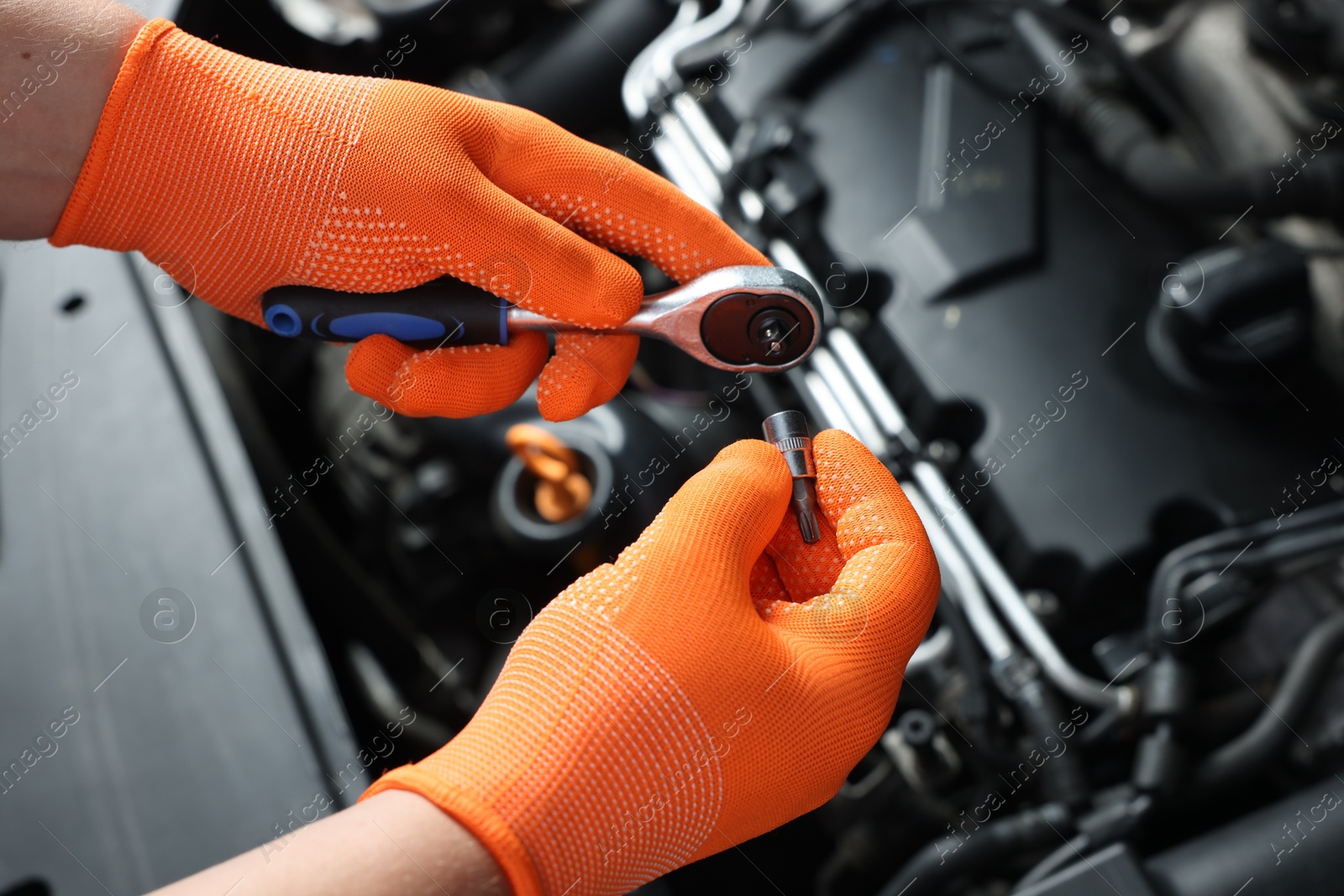 Photo of Auto mechanic with torque wrench fixing car at automobile repair shop, closeup