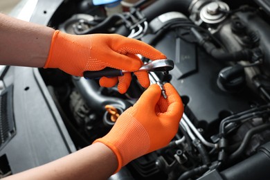 Photo of Auto mechanic with torque wrench fixing car at automobile repair shop, closeup