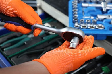 Auto mechanic with torque wrench and different tools at automobile repair shop, closeup