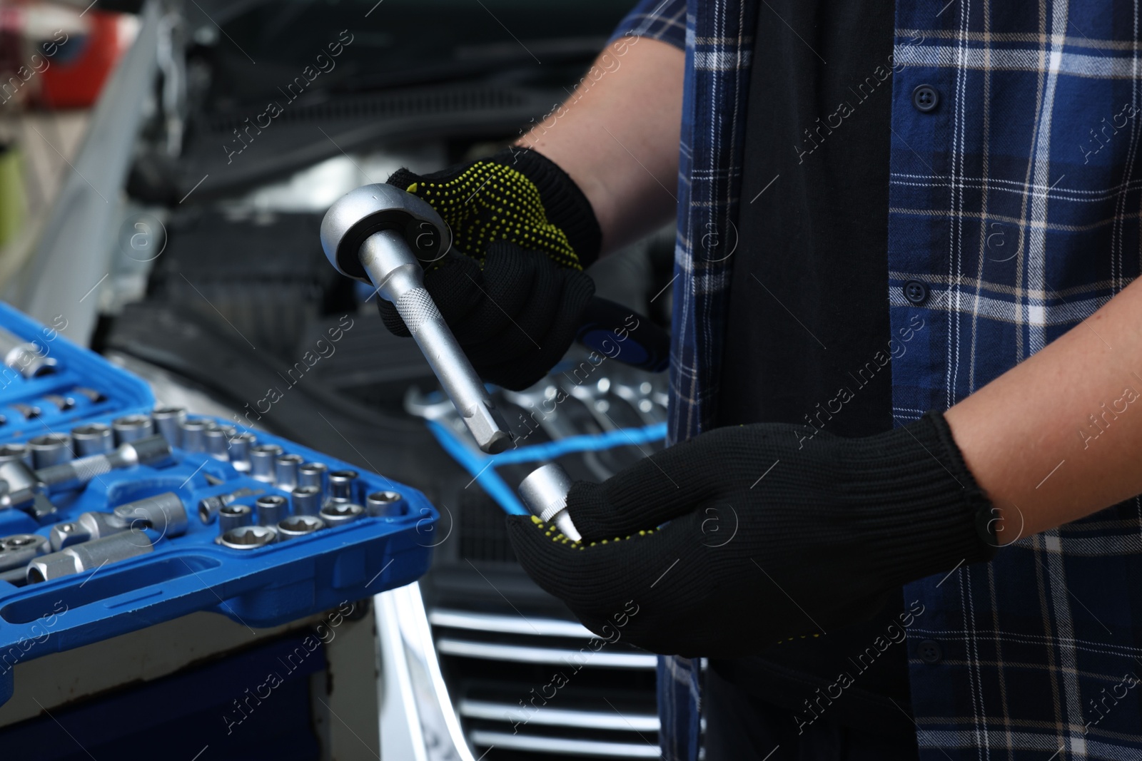 Photo of Auto mechanic with torque wrench at automobile repair shop, closeup