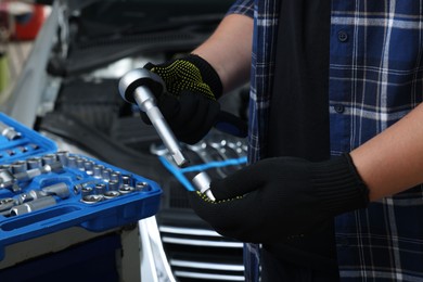 Photo of Auto mechanic with torque wrench at automobile repair shop, closeup