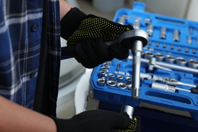 Auto mechanic with torque wrench at automobile repair shop, closeup