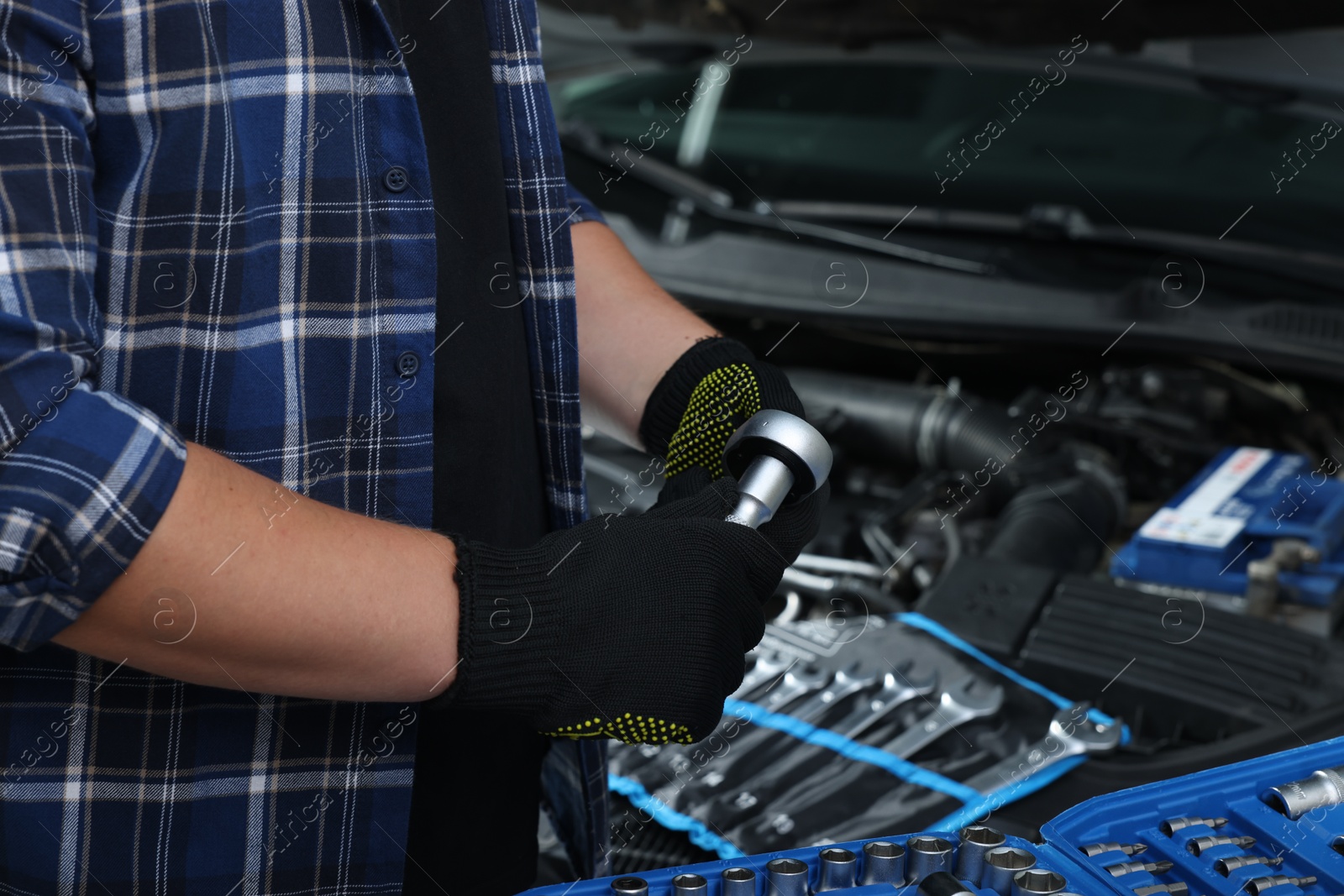 Photo of Auto mechanic with torque wrench at automobile repair shop, closeup