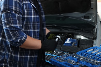 Auto mechanic with torque wrench at automobile repair shop, closeup