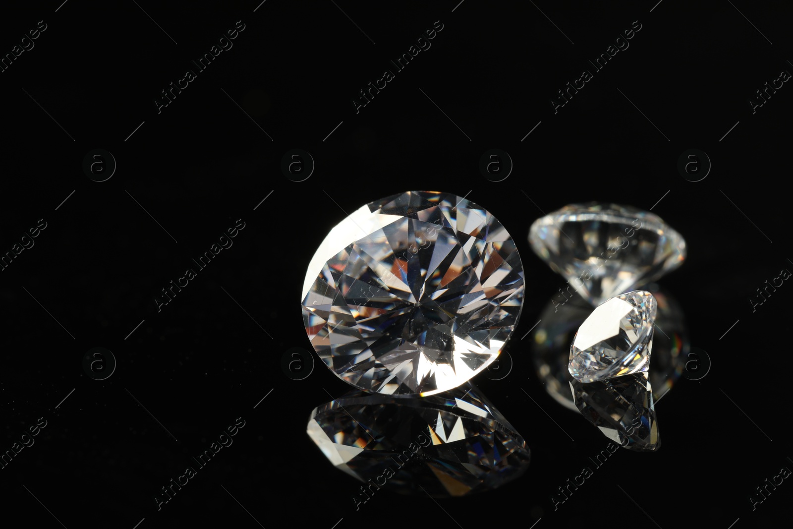 Photo of Beautiful shiny diamonds on black mirror surface, closeup. Space for text