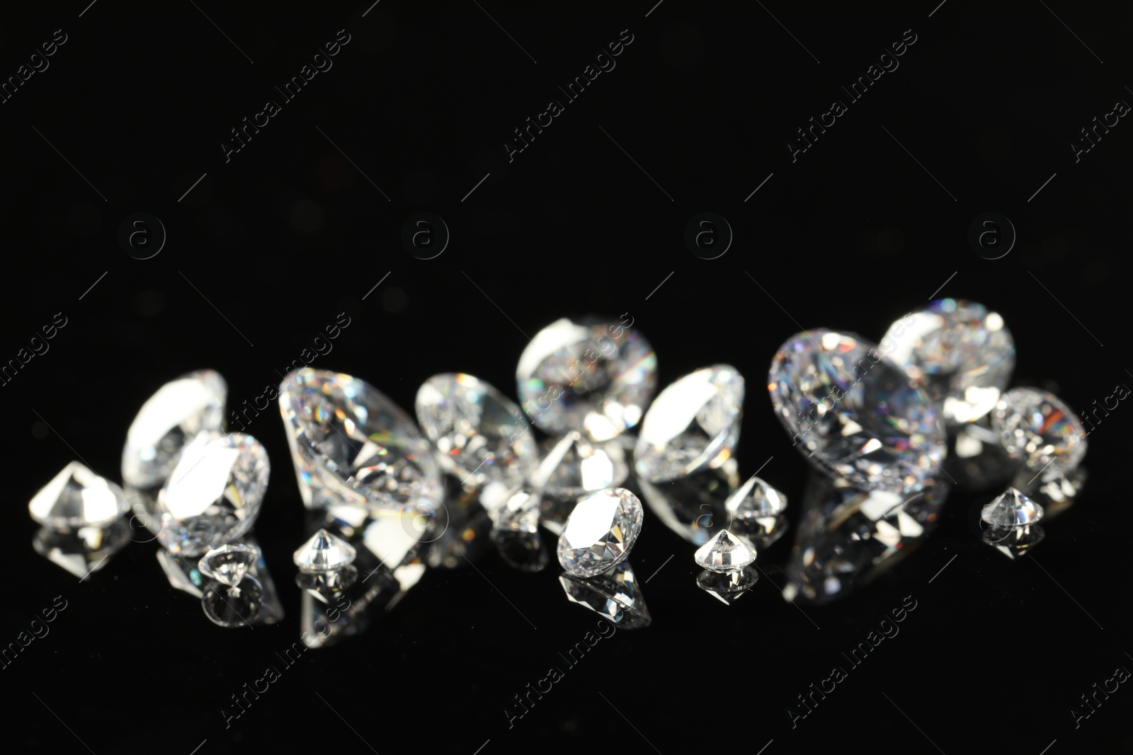 Photo of Many beautiful shiny diamonds on black mirror surface, closeup