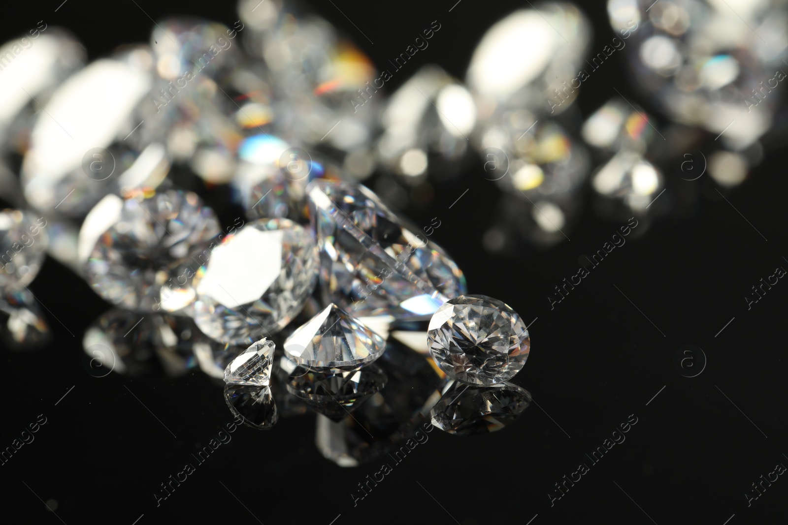 Photo of Many beautiful shiny diamonds on black mirror surface, closeup