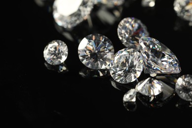 Many beautiful shiny diamonds on black mirror surface, closeup