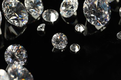 Photo of Many beautiful shiny diamonds on black mirror surface, closeup