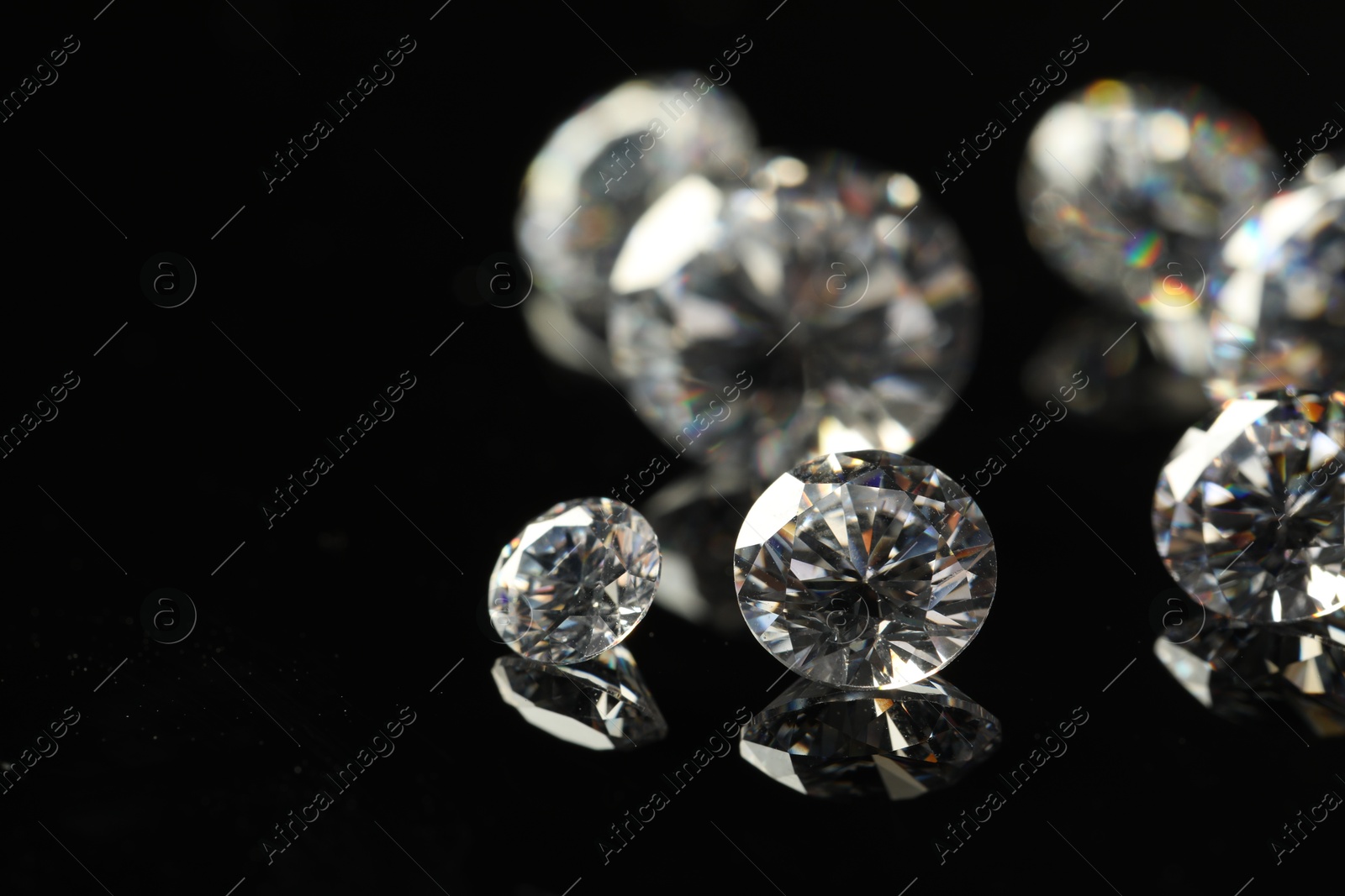 Photo of Many beautiful shiny diamonds on black mirror surface, closeup. Space for text