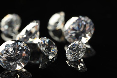 Photo of Many beautiful shiny diamonds on black mirror surface, closeup