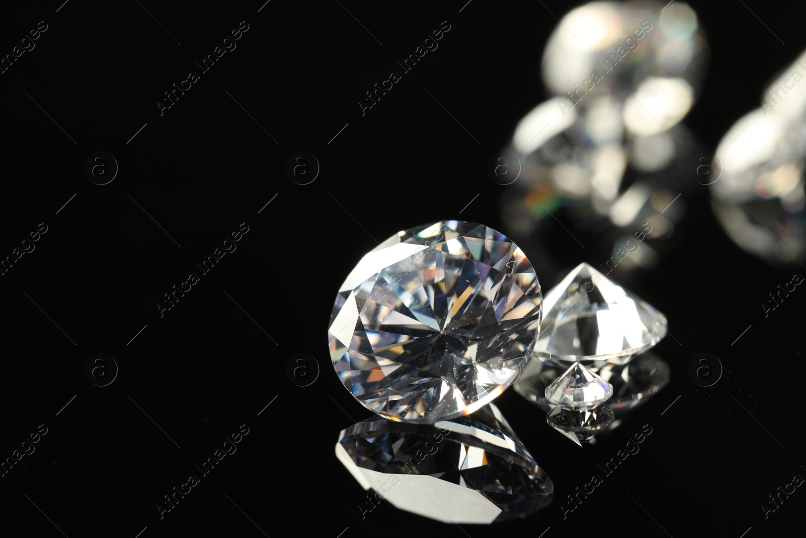 Photo of Beautiful shiny diamonds on black mirror surface, closeup. Space for text