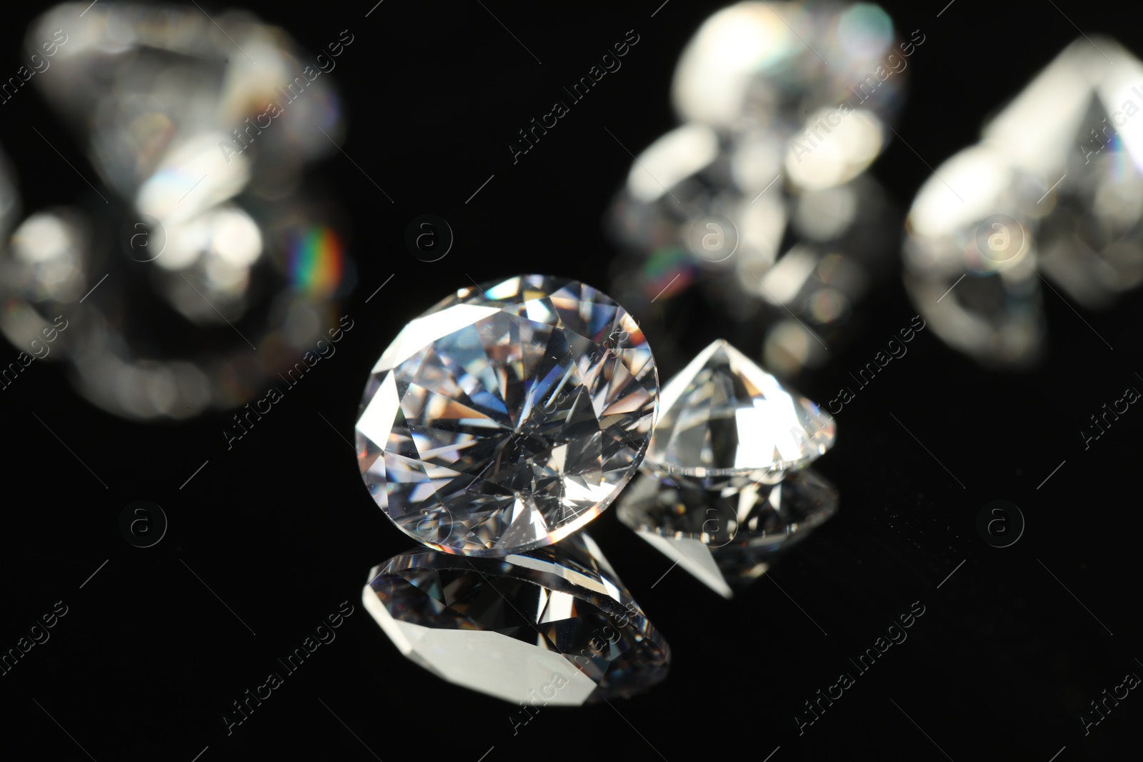 Photo of Beautiful shiny diamonds on black mirror surface, closeup