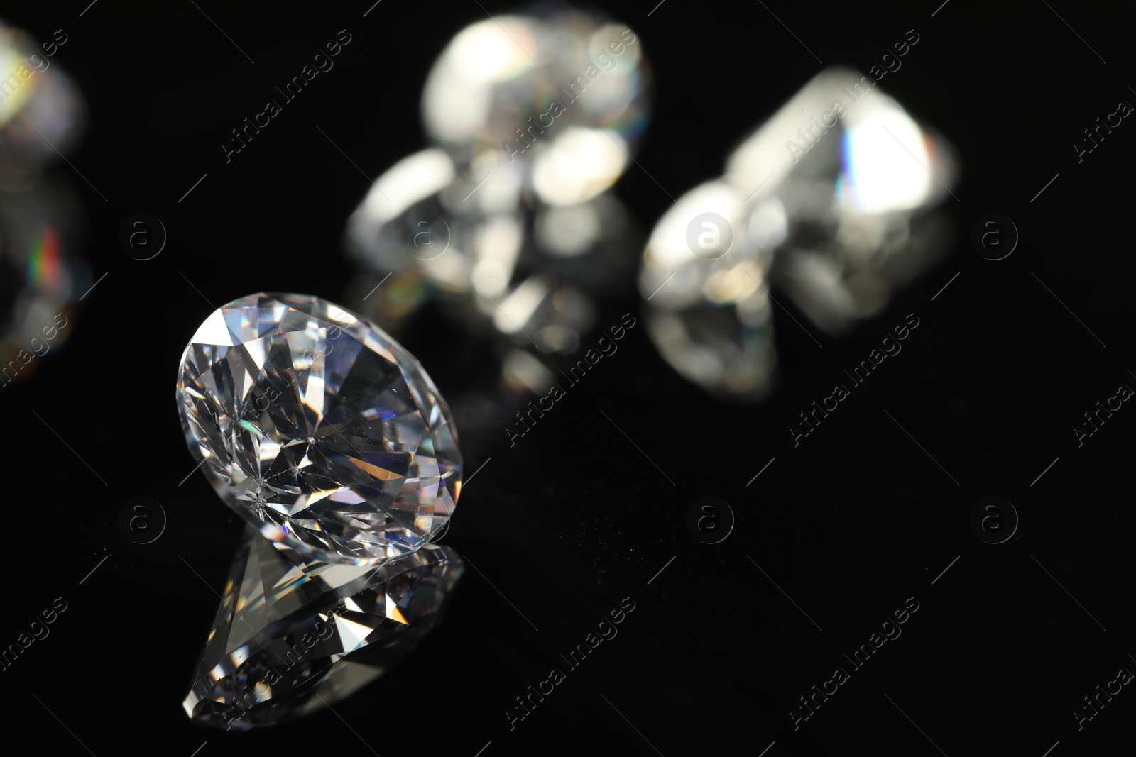 Photo of Beautiful shiny diamond on black mirror surface, closeup. Space for text